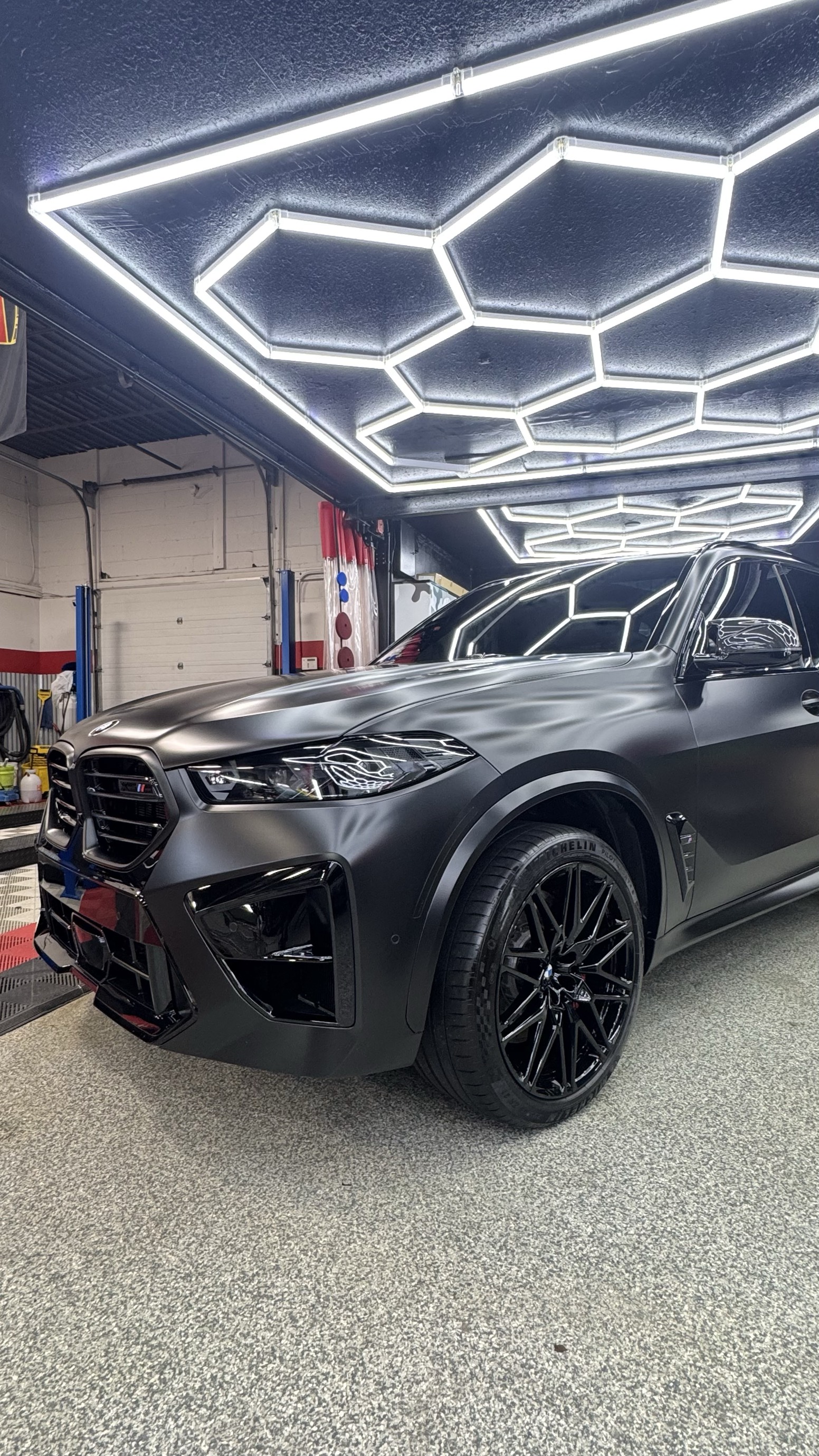 Matte black BMW X5 M under hexagon lights